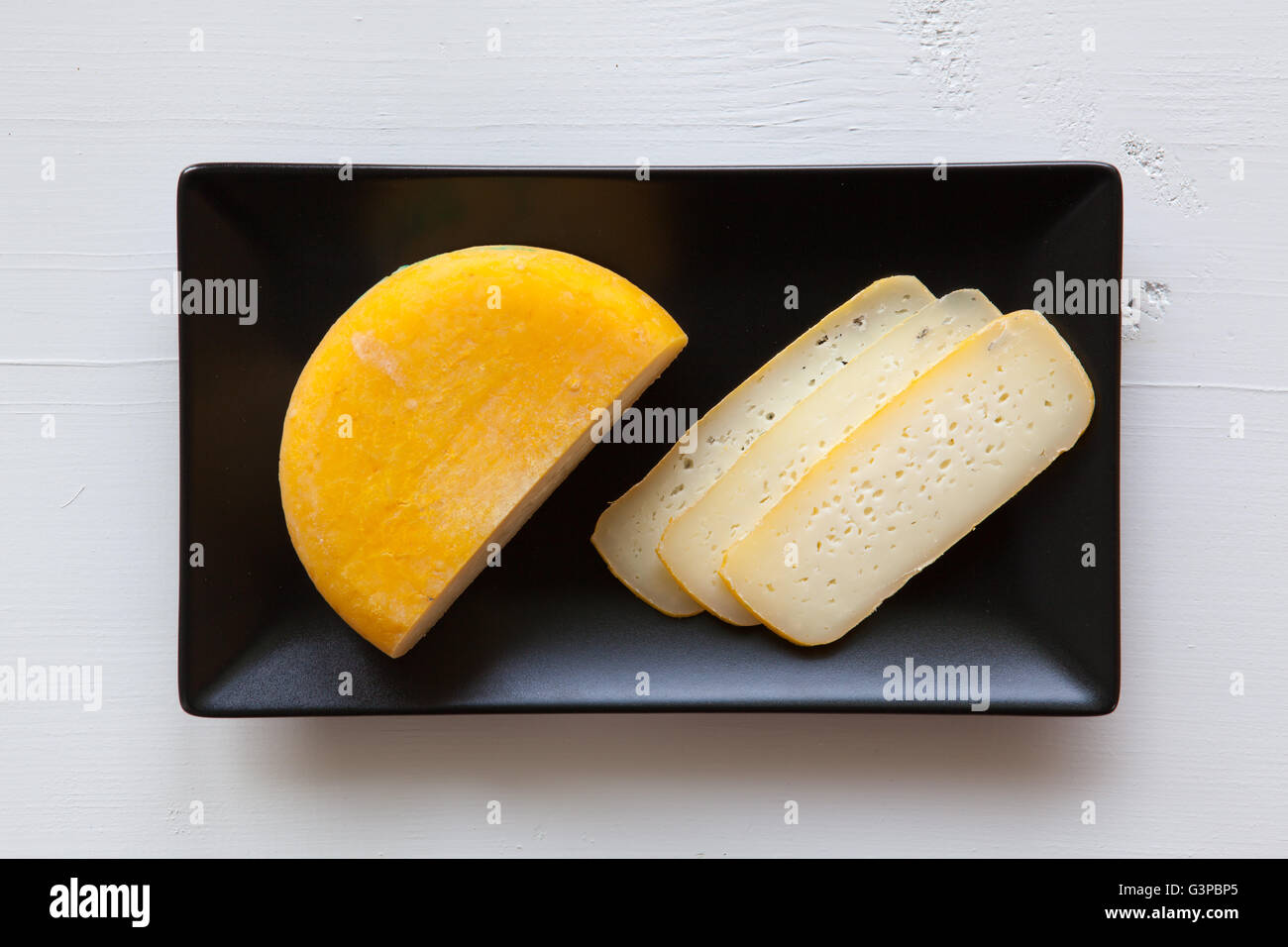 Rectangle en céramique noire avec des plats de fromage savoureux bloc isolé sur un bureau en bois blanc Banque D'Images