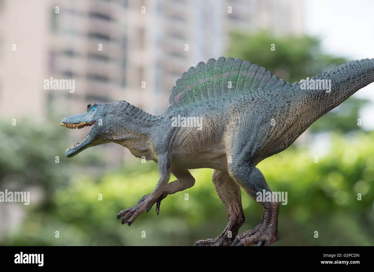 Spinosaurus gris jouet en avant du bâtiment et arbres Banque D'Images