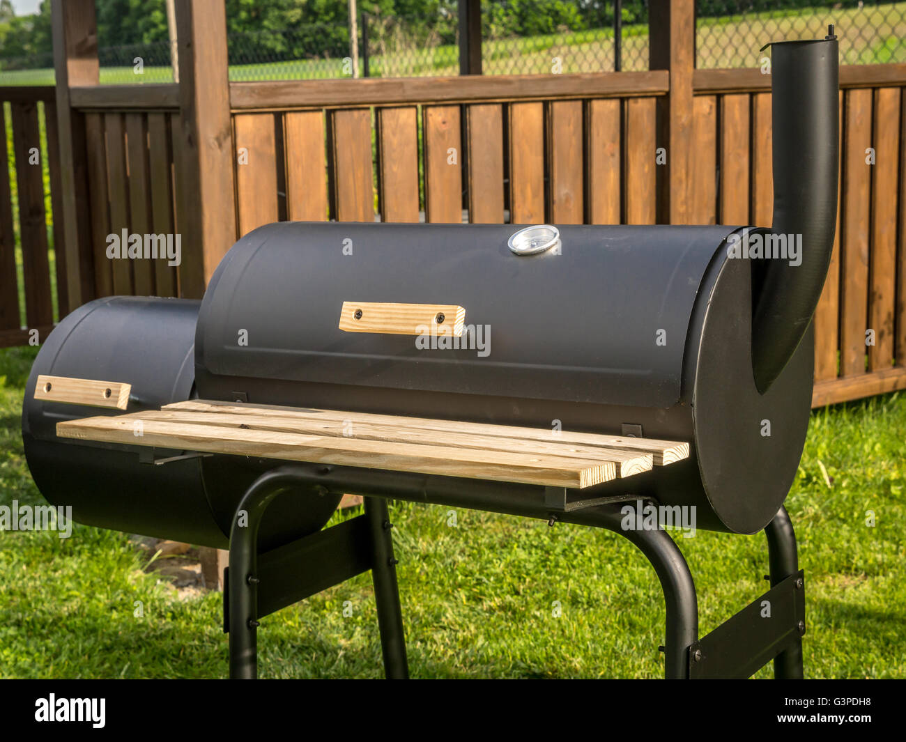 Grill noir avec cheminée en bois avec maison d'été dans l'arrière-plan Banque D'Images