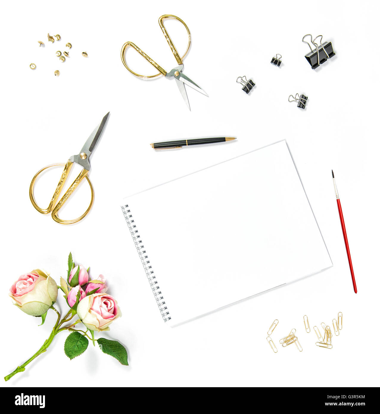 Mise à plat avec un carnet de croquis, aquarelle pinceau, outils office, fleurs rose sur fond blanc Banque D'Images
