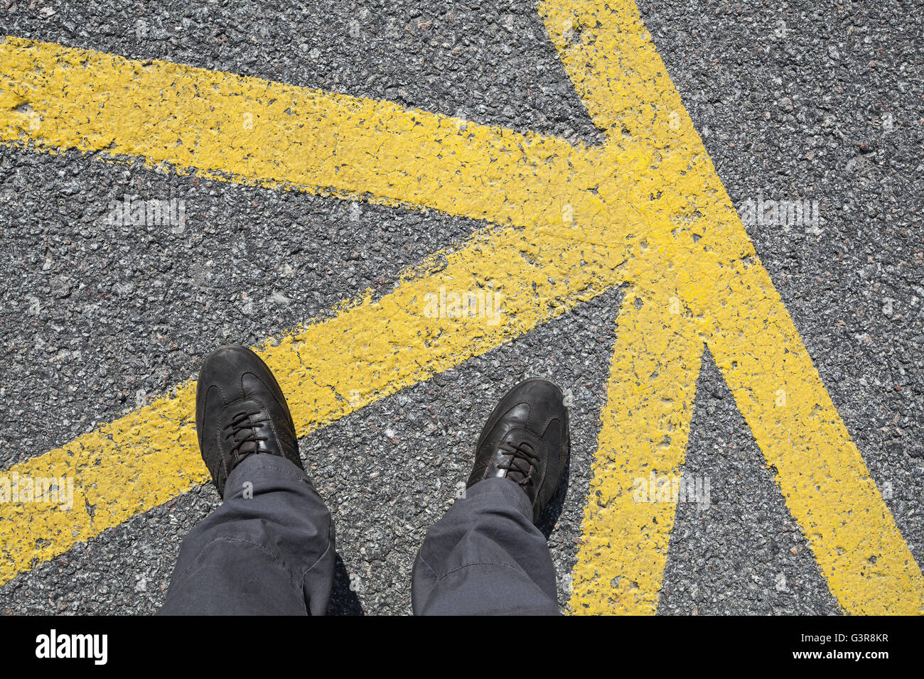Chaussures en cuir hommes pieds en position sur le trottoir d'asphalte avec des lignes de marquage routier jaune, vue à la première personne Banque D'Images
