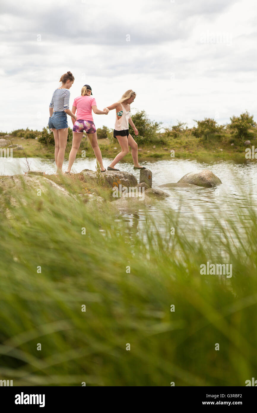 La Suède, Blekinge, Solvesbor, le torse, les adolescentes (14-15) walking on rocks in water Banque D'Images