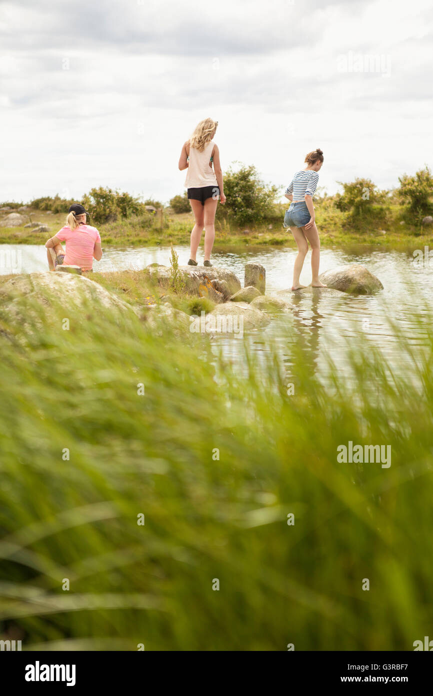 La Suède, Blekinge, Solvesbor, le torse, les adolescentes (14-15) walking on rocks in water Banque D'Images