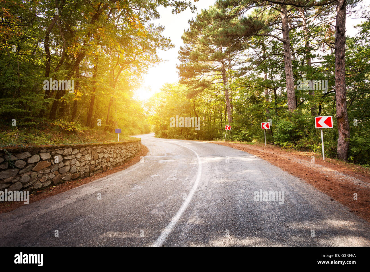 Beau paysage et route asphaltée,forêt verte et signe de route au lever du soleil coloré en été. Montagnes de Crimée.Travel background Banque D'Images