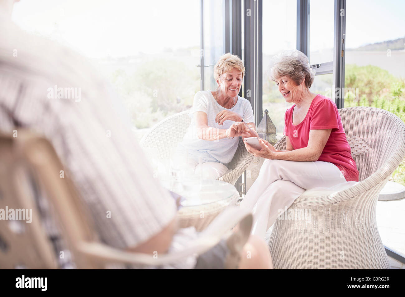 Les femmes âgées using cell phone on patio Banque D'Images