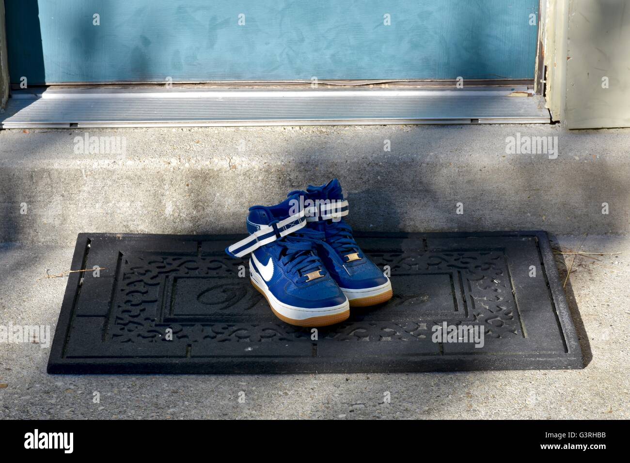 Une paire de chaussures Nike bleu assis sur un tapis de porte en face d'une maison Banque D'Images