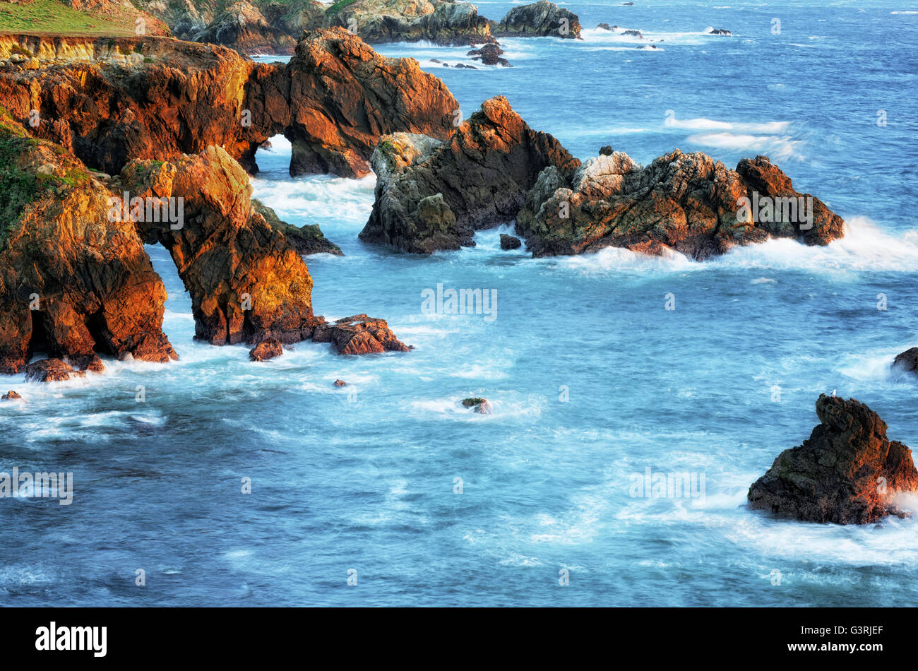 Lumière du soir baigne les vagues se brisant sur la côte sauvage de la Californie Big Sur. Banque D'Images