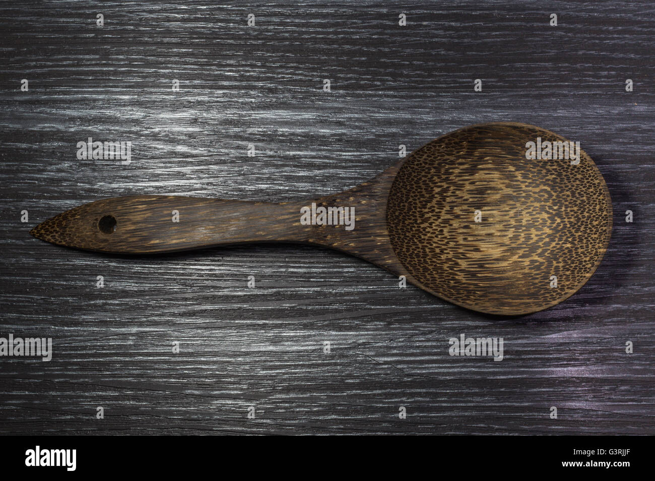 Cuillère en bois brun noir sur fond de textures de bois Banque D'Images