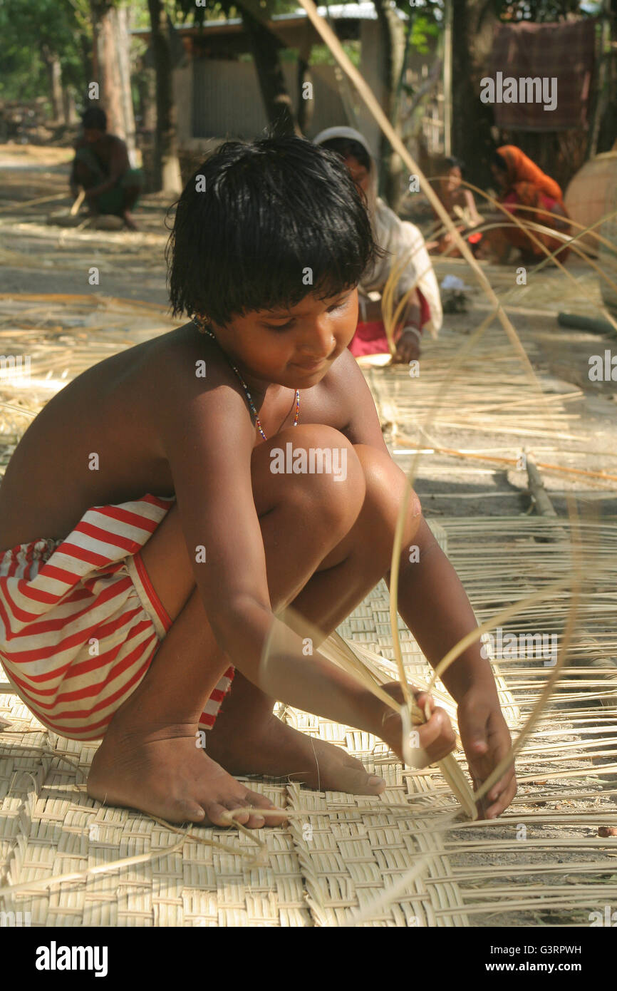 Un enfant faisant un panier de bambou .Mangla,Bangladesh. Banque D'Images