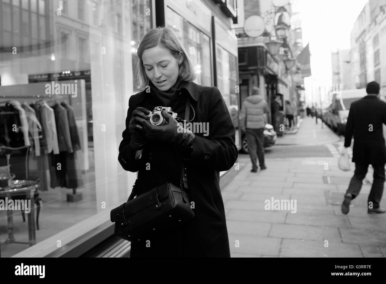 Dame élégante avec vintage Leica Camera taking photograph in Dover Street, Mayfair, Londres. Banque D'Images