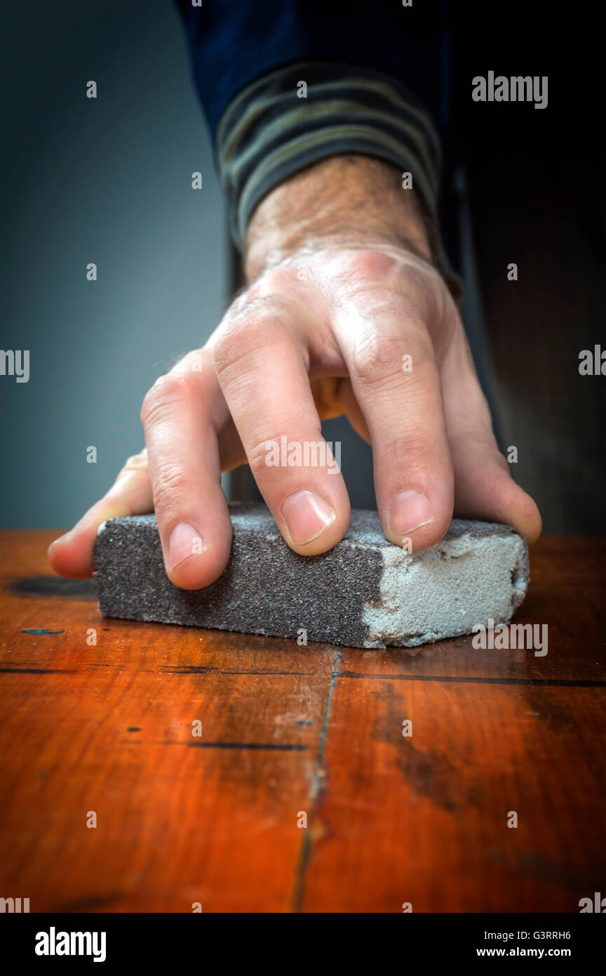 Homme à travailler avec du papier de verre sur une planche de bois. Banque D'Images