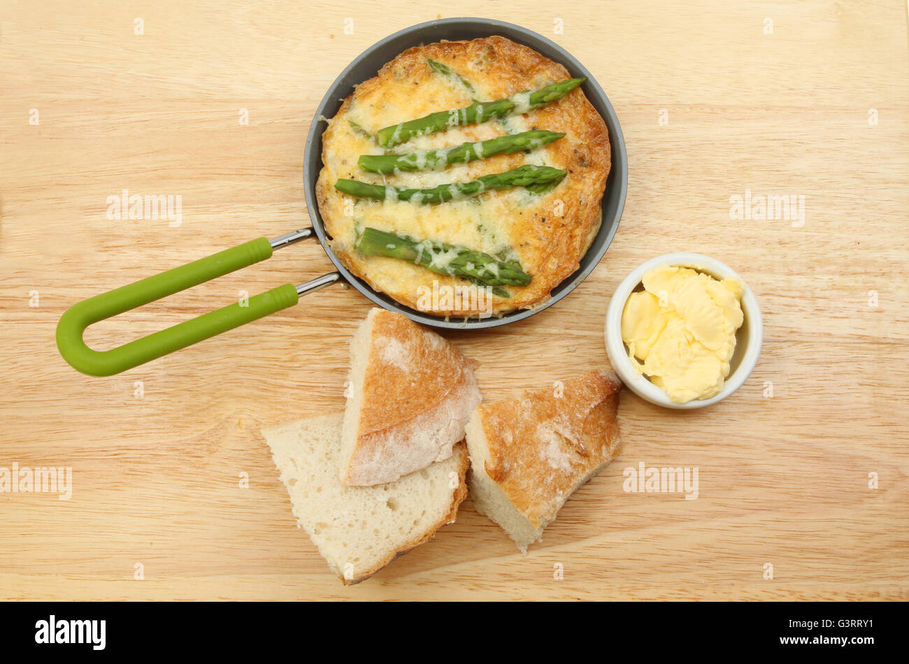 Frittata aux asperges et fromage individuel avec du pain croustillant et du beurre sur un woodwn chopping board Banque D'Images