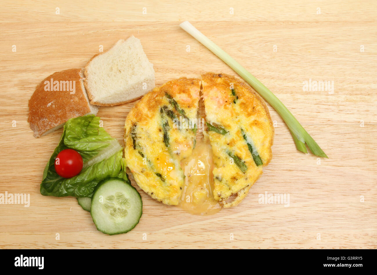 Frittata aux asperges et fromage avec salade et pain croustillant sur une planche à découper en bois Banque D'Images