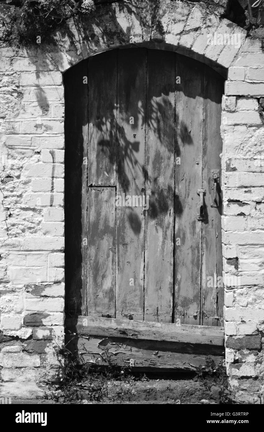 Vieille porte en bois, la peinture écaillée, entouré de mur blanc avec porte voûtée haut Banque D'Images