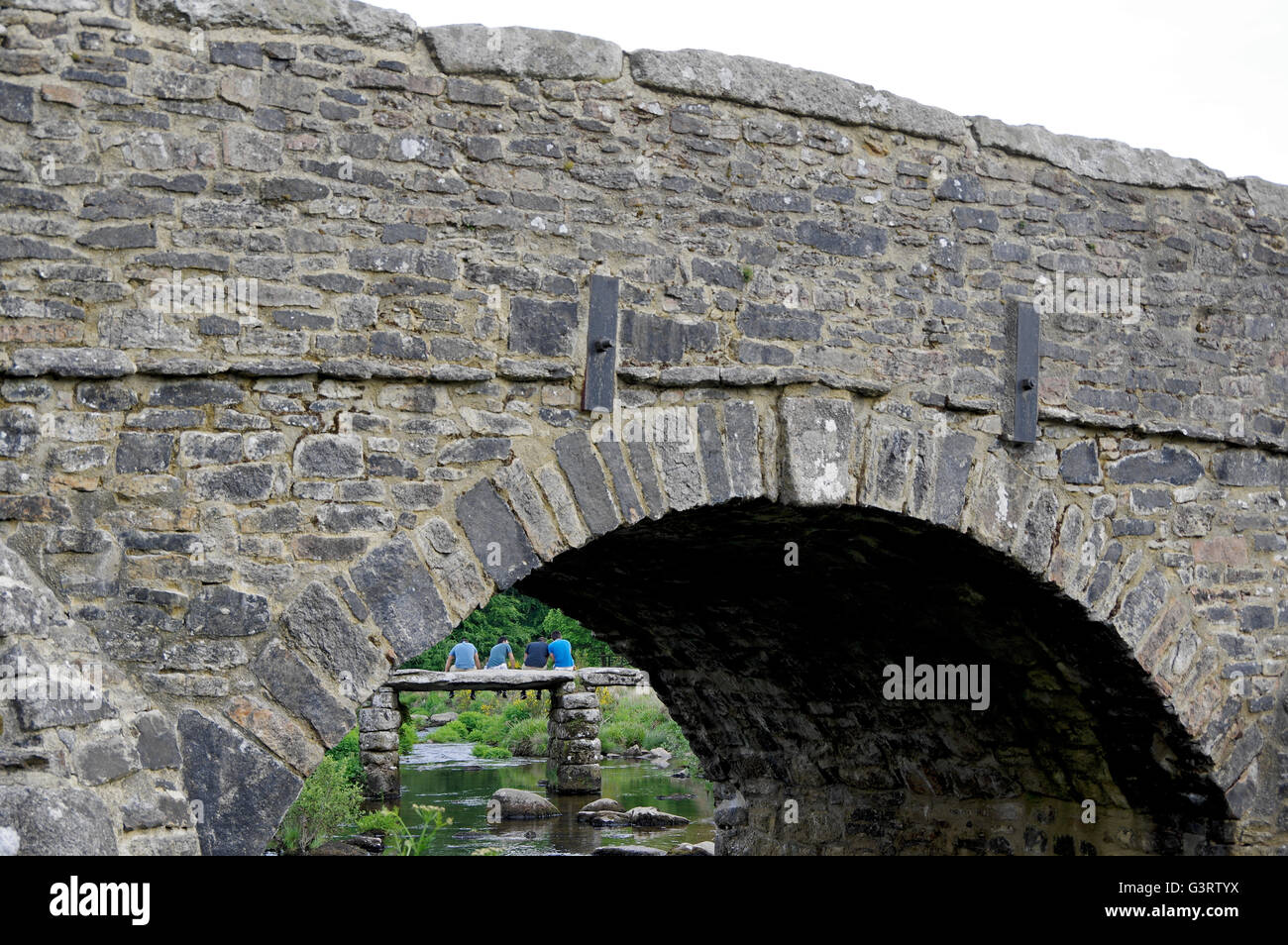 Vue à travers une arche de la 18e siècle pont sur la rivière dart de l'est vers des gens assis sur l'antique pont battant. Banque D'Images