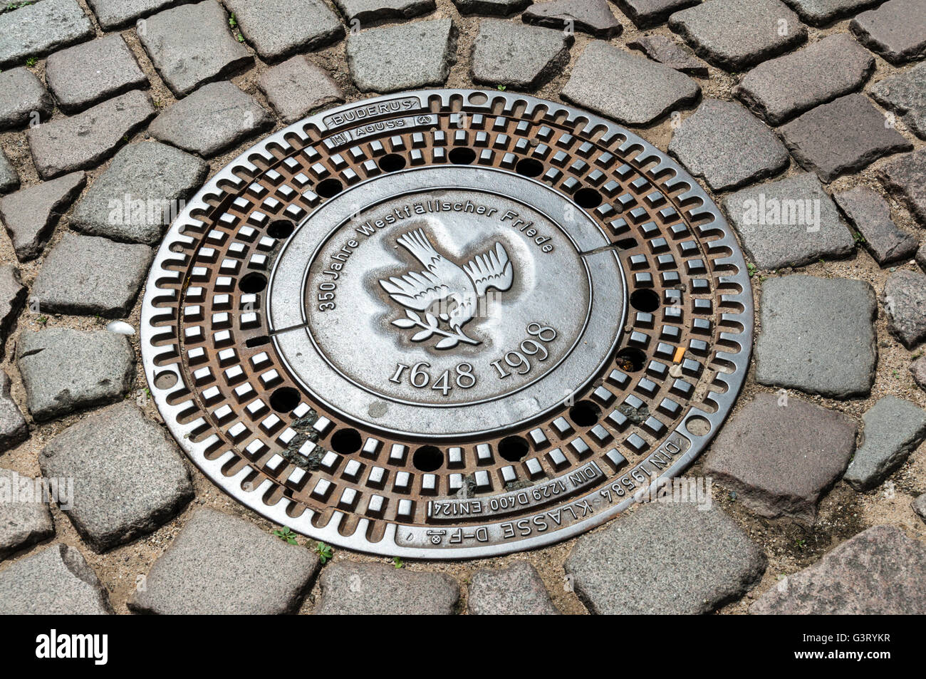 Le couvercle de trou d'homme-décoratif sur rue pavée, à Münster, NRW, Allemagne. Banque D'Images