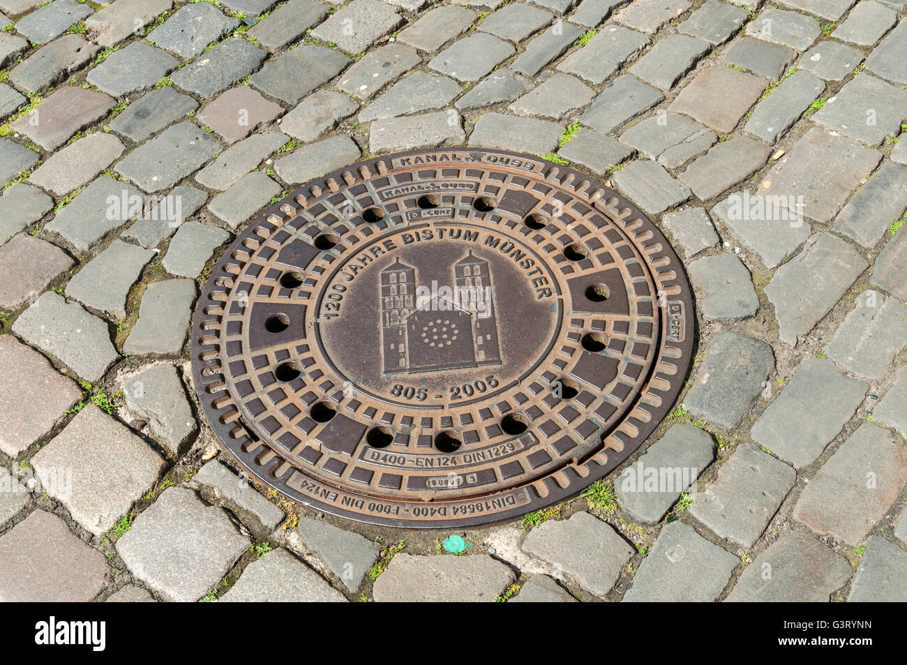 Le couvercle de trou d'homme-décoratif sur rue pavée, à Münster, NRW, Allemagne. Banque D'Images