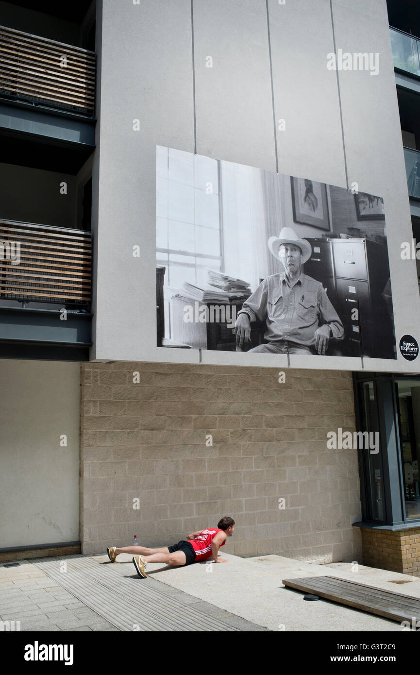 Un homme fait un yoga pose sous une grande photo, partie d'une exposition locale posté sur les murs Banque D'Images