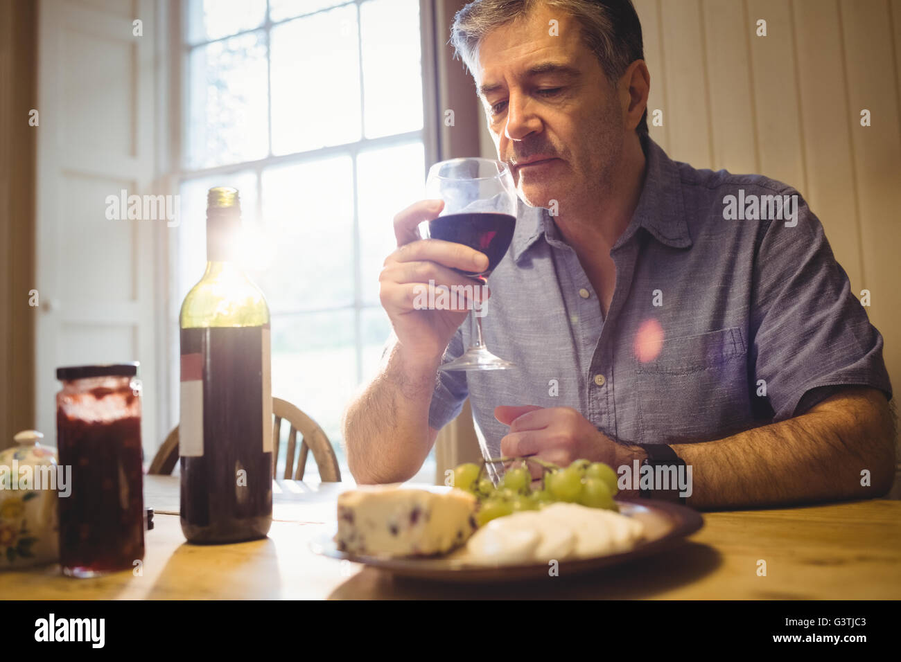 Young man sitting at table et dégustation de vin rouge Banque D'Images