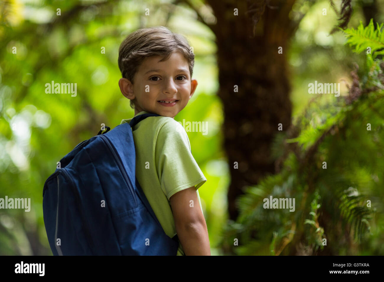 Smiling boy standing in forest Banque D'Images