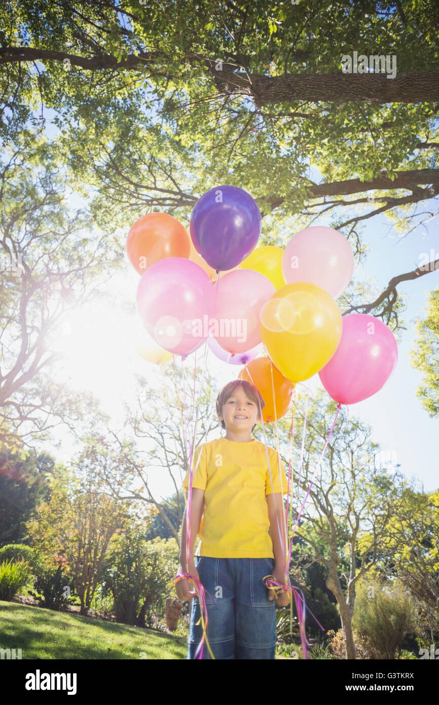 Portrait of smiling boy holding balloons in park Banque D'Images