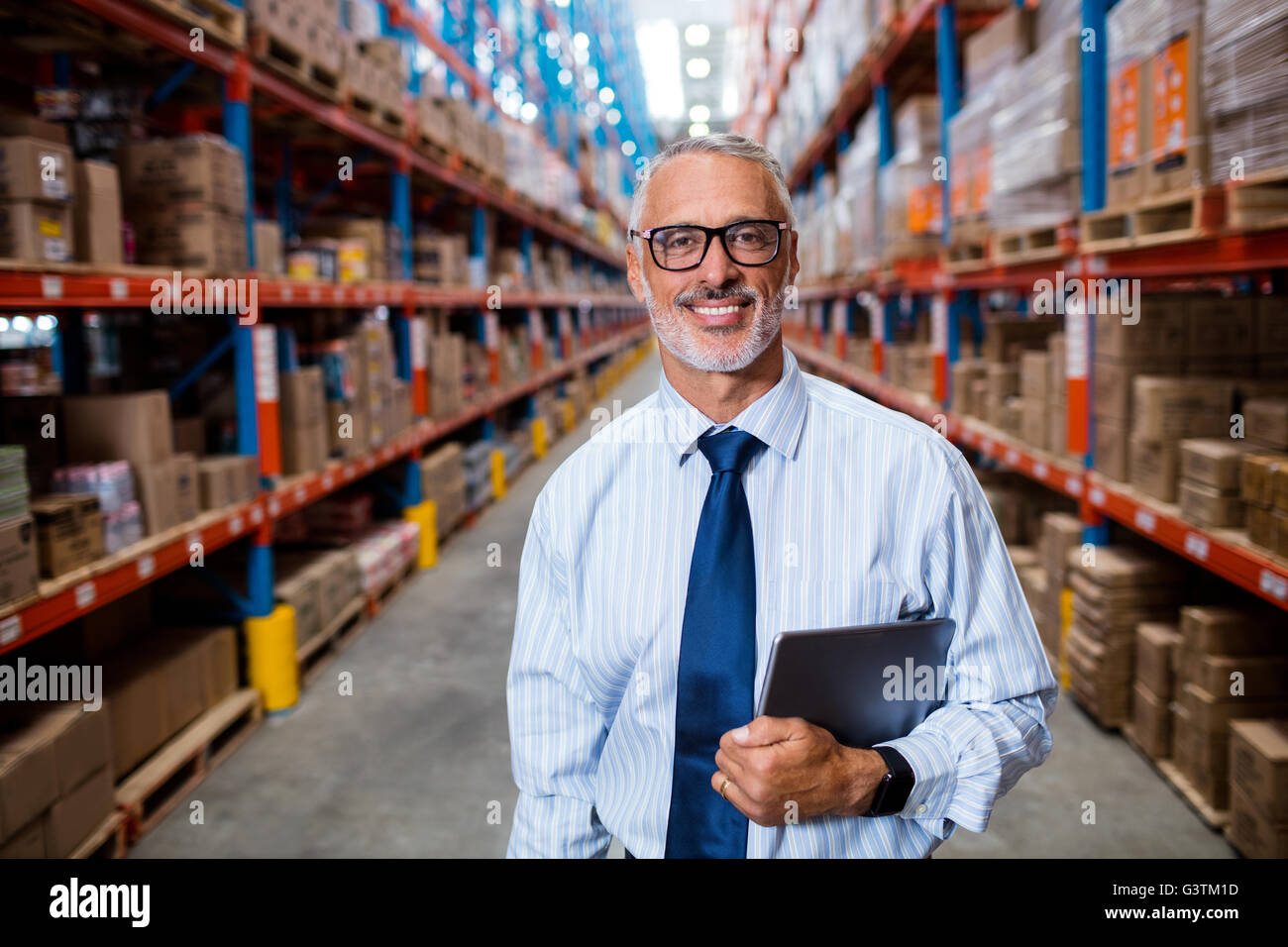 La moitié de la longueur de Warehouse Manager holding his tablet computer Banque D'Images