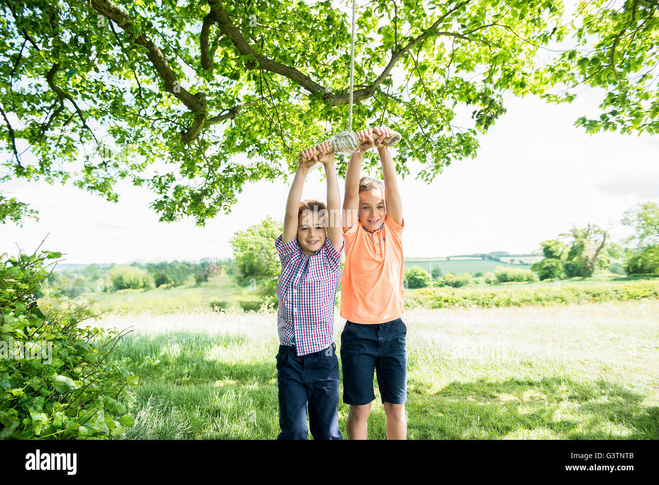 Deux garçons jouant sur une balançoire dans la campagne. Banque D'Images