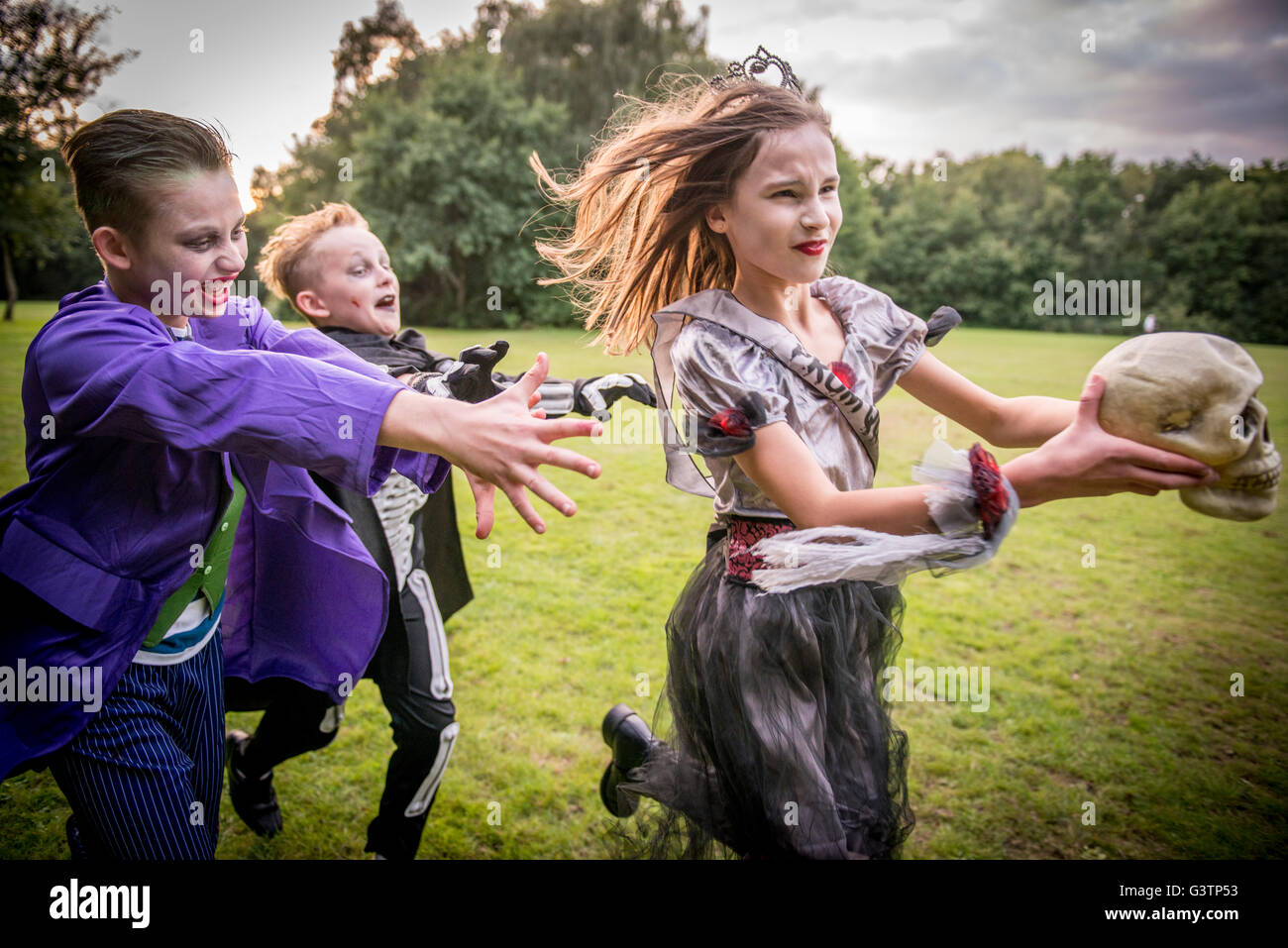 Enfants chase une fille habillé comme un zombie prom queen pour l'Halloween. Banque D'Images