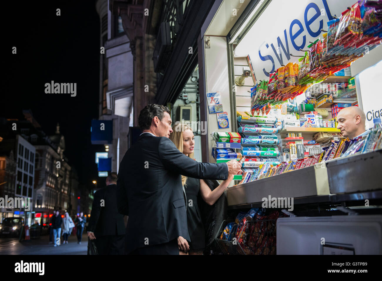 Un couple qui achète des confiseries habillés à partir d'un kiosque sur Oxford Street à Londres. Banque D'Images