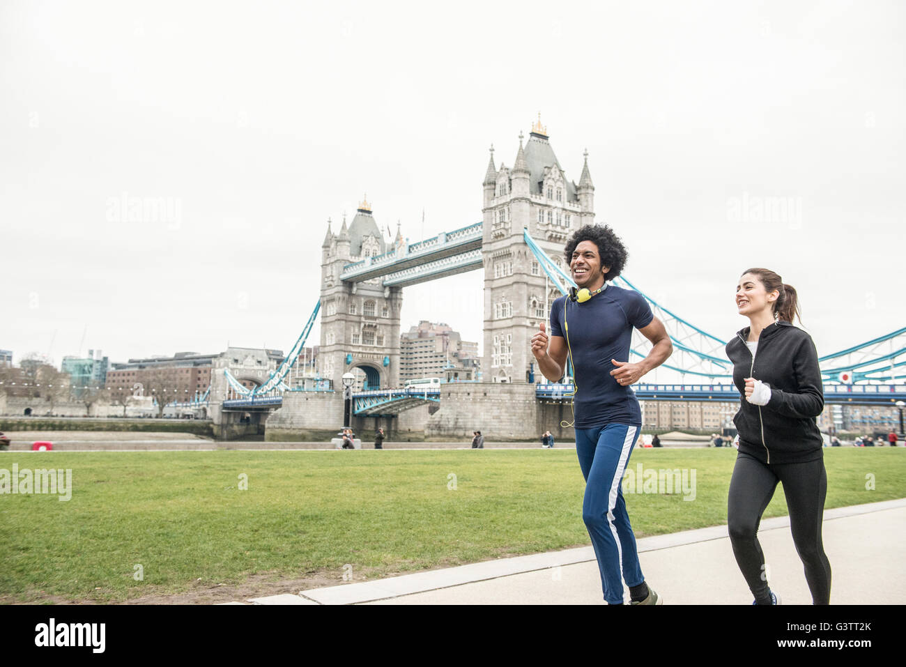 Un jeune couple jogging ensemble passé le Tower Bridge à Londres. Banque D'Images