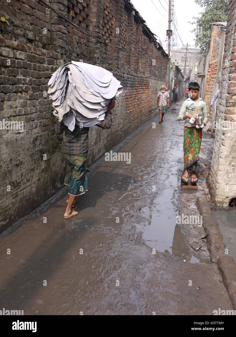 Dans la région de Hazaribagh, Dhaka, Bangladesh, les enfants travaillent pour les tanneries, tandis que l'eau pleine de produit chimique dangereux dans les rues d'écoulement Banque D'Images