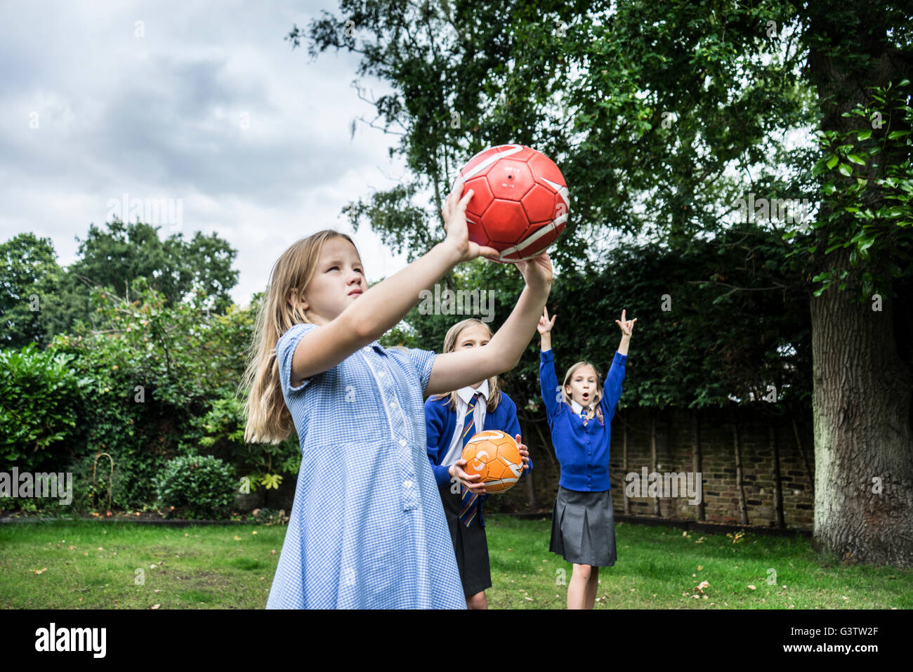 Trois jeunes filles en uniforme d'jouant avec des ballons de l'extérieur. Banque D'Images