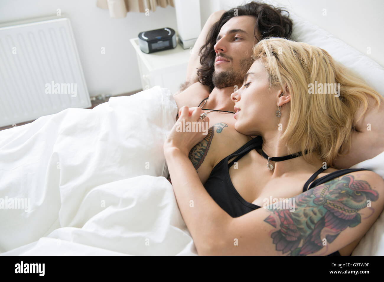 Un jeune couple cool tatoué dans un lit. Banque D'Images