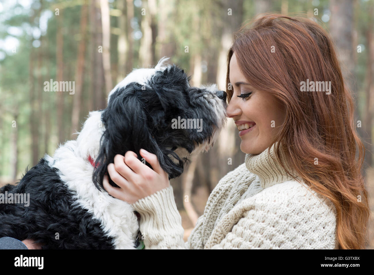Une jeune femme de caresser un chien sur une forêt Promenade en automne. Banque D'Images