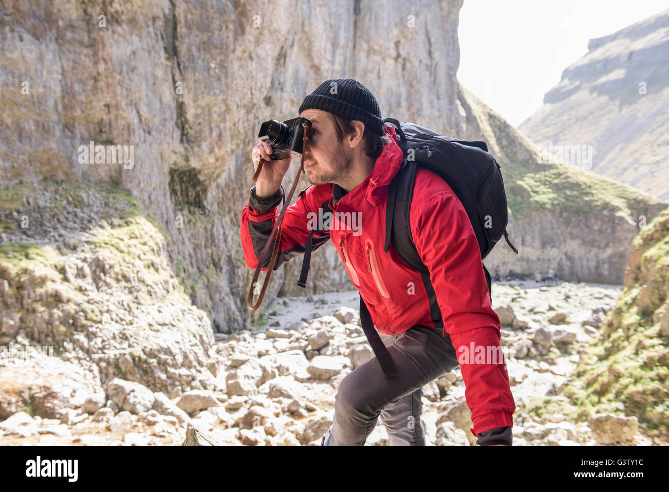 L'alpiniste escalade sur les rochers, de prendre des photographies dans un terrain accidenté. Banque D'Images