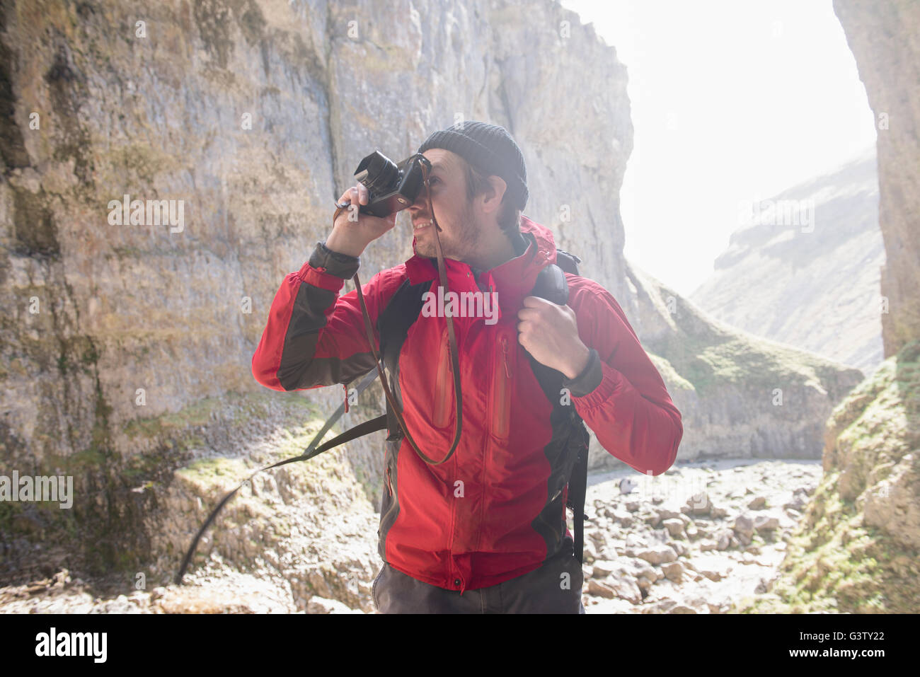 L'alpiniste escalade sur les rochers, de prendre des photographies dans un terrain accidenté. Banque D'Images