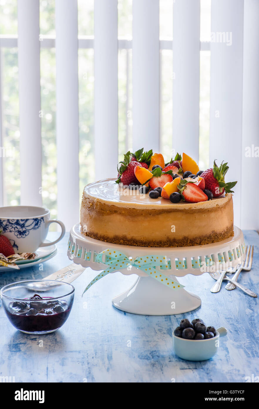 Cheesecake au caramel avec le lait caillé de citron sur cakestand avec sauce aux bleuets, décorées avec des baies fraîches. Selective focus, vertical Banque D'Images