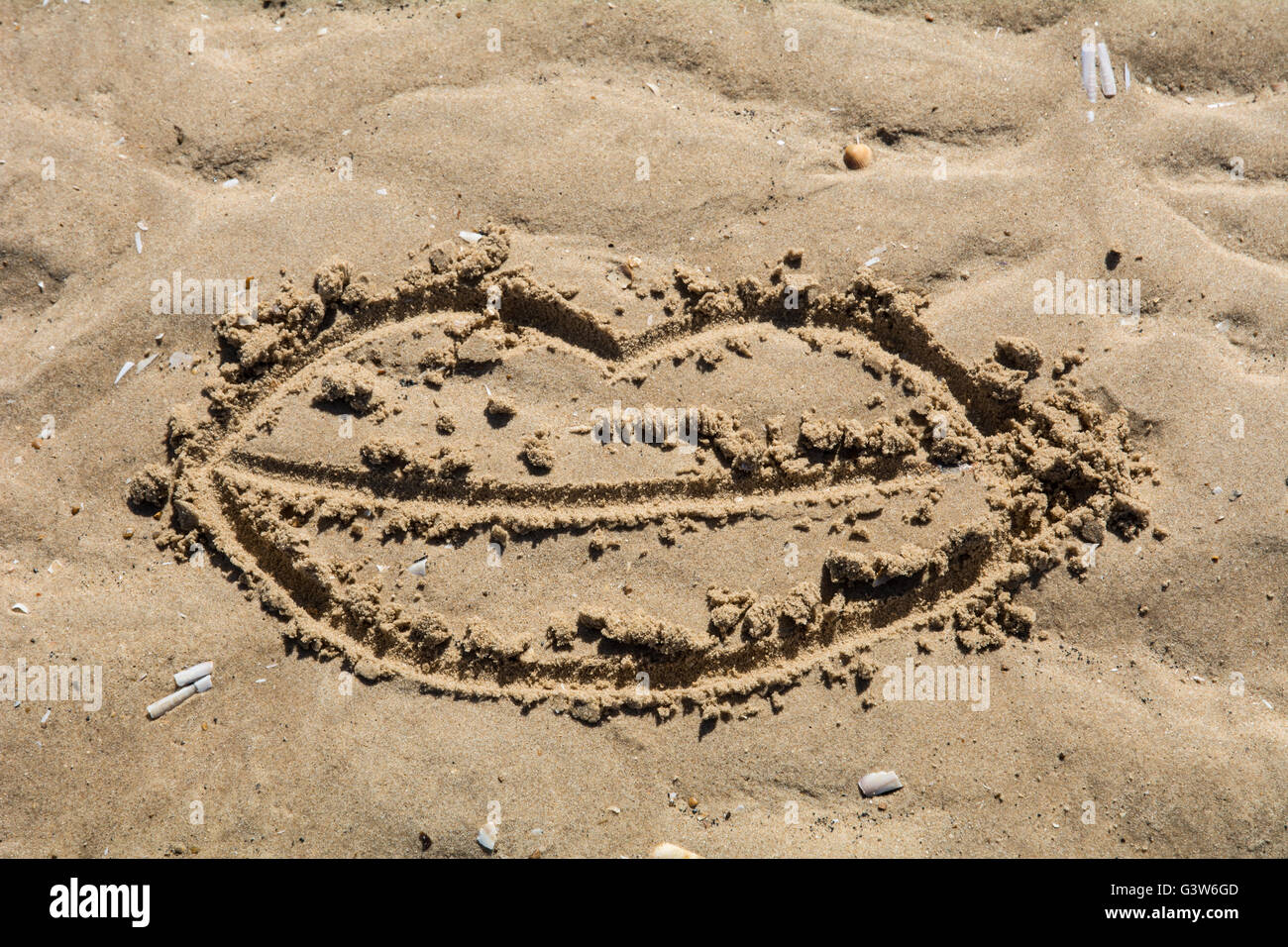 Une paire de lèvres dessiné dans le sable. Banque D'Images