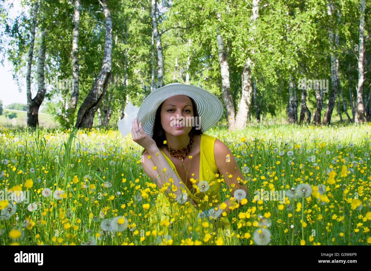 La jeune fille dans un chapeau sur une prairie entre les fleurs jaunes et les pissenlits, la jeune fille, sur un pré, le bois, le jaune, les fleurs, les jeunes Banque D'Images