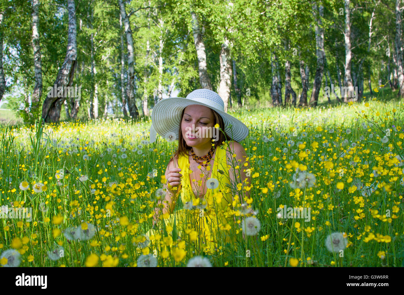La jeune fille dans un chapeau sur une prairie entre les fleurs jaunes et les pissenlits, la jeune fille, sur un pré, le bois, le jaune, les fleurs, les jeunes Banque D'Images