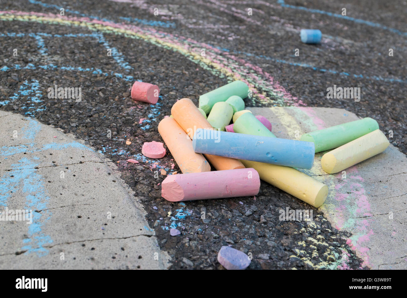 Close up d'un tas de morceaux de craie de couleur sur une route avec des dessins sur le tarmac Banque D'Images