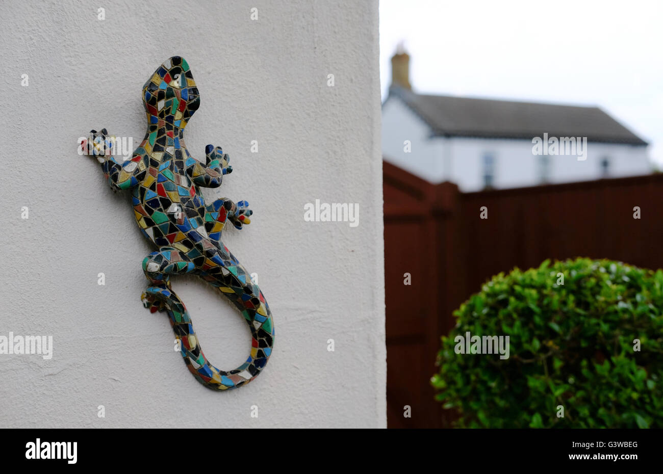 Grand lézard décoratif en mosaïque vu sur le côté d'un mur de chalet. Banque D'Images