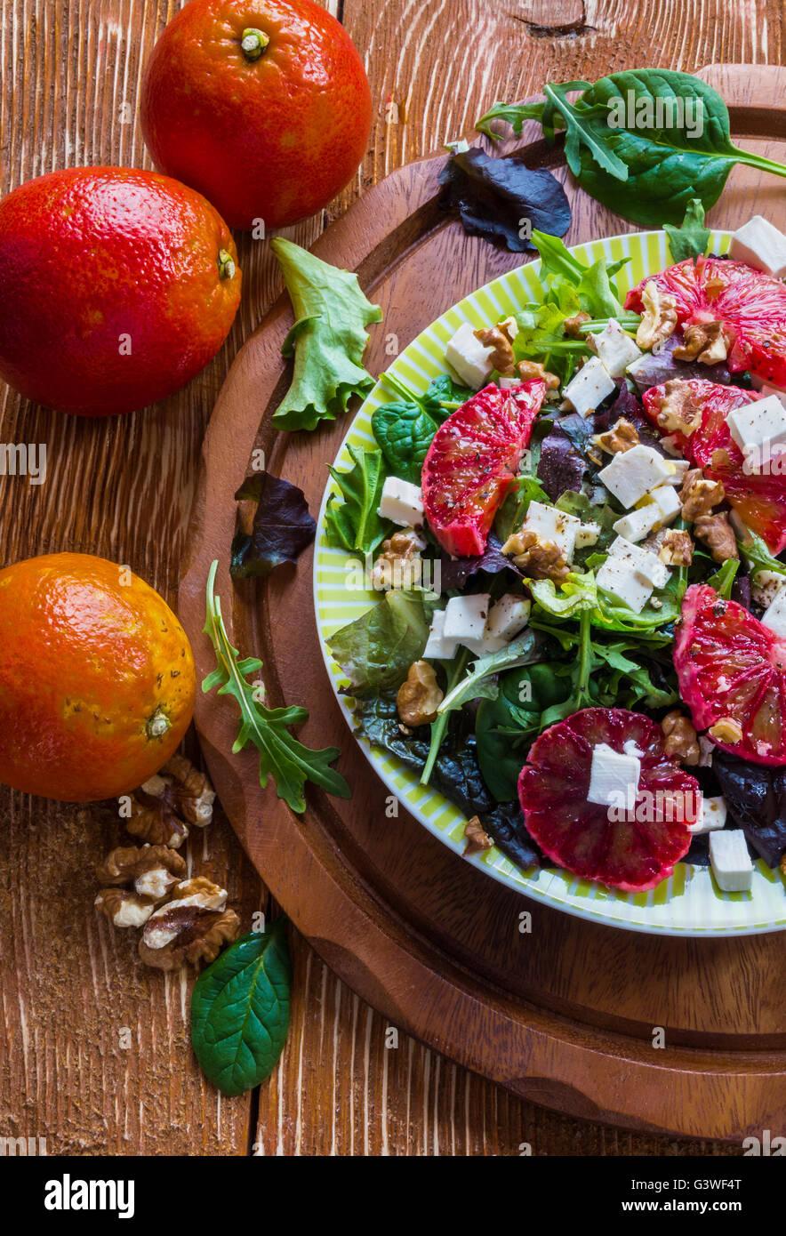 Salade : mélange de salade verte, fromage feta, rouge orange et noix. Vinaigrette : huile d'olive. Selective focus, vue du dessus. Banque D'Images