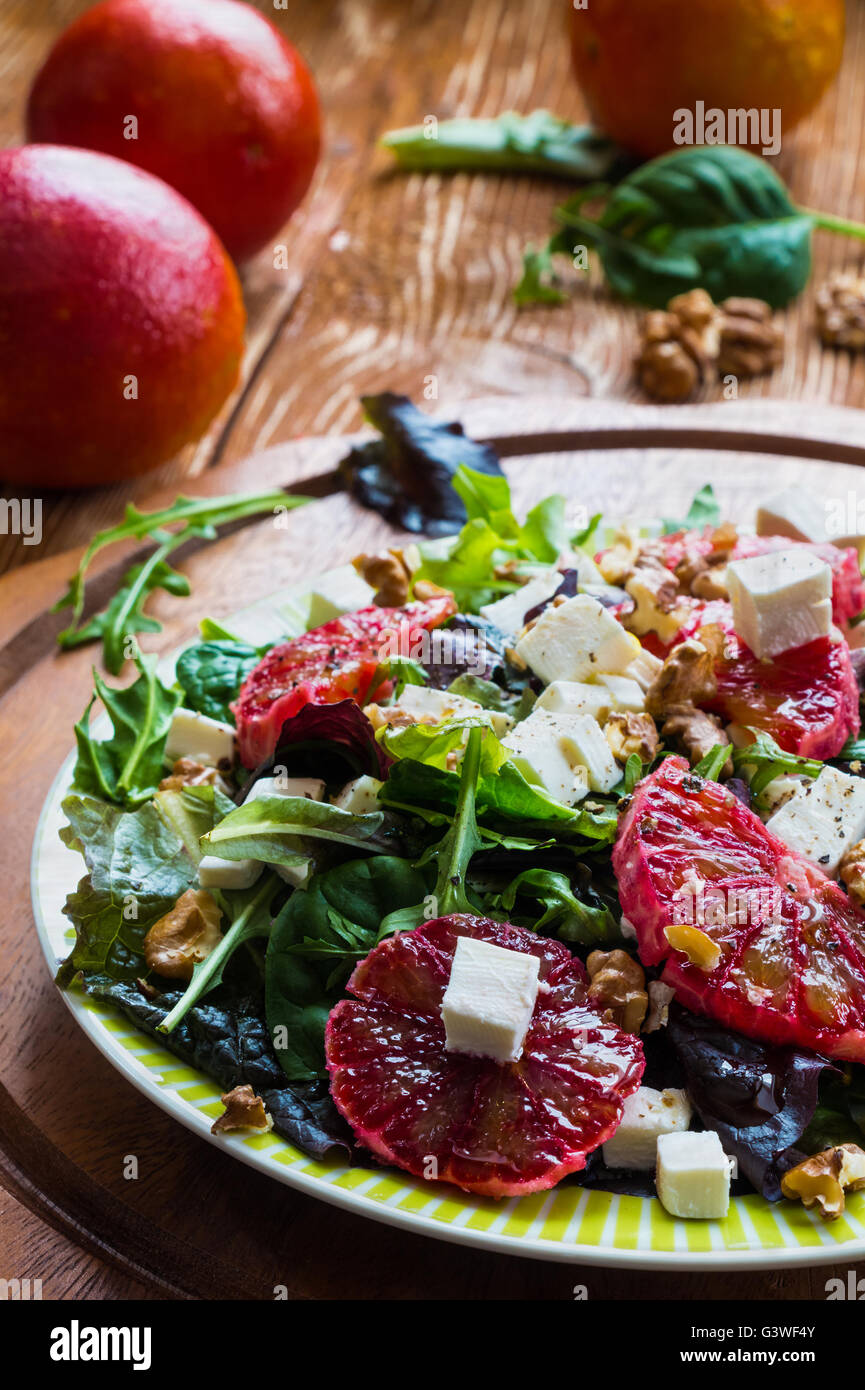 Salade : mélange de salade verte, fromage feta, rouge orange et noix. Vinaigrette : huile d'olive. Focus sélectif. Banque D'Images