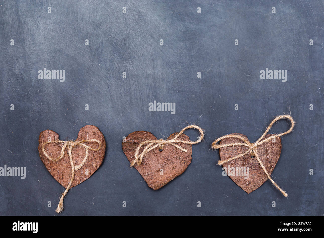 Trois (3) coeurs décoratifs fabriqués à partir de l'écorce des arbres sur tableau, idée de carte de vœux. Décoration éco. Banque D'Images