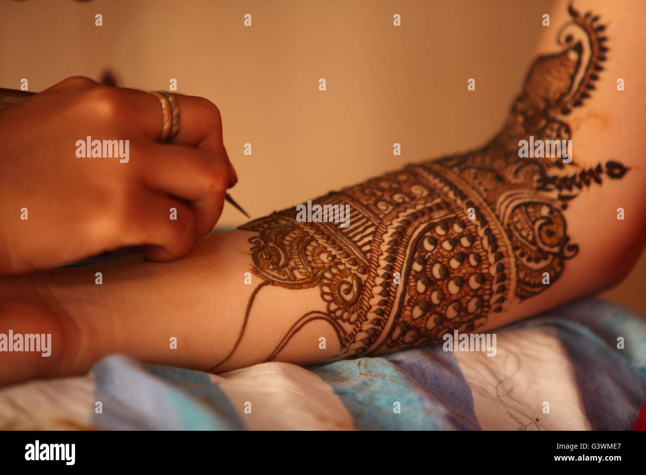 Un artiste de faire un design traditionnel de jolis motifs de henné ou mehendi sur les mains d'une Indienne mariée. Banque D'Images