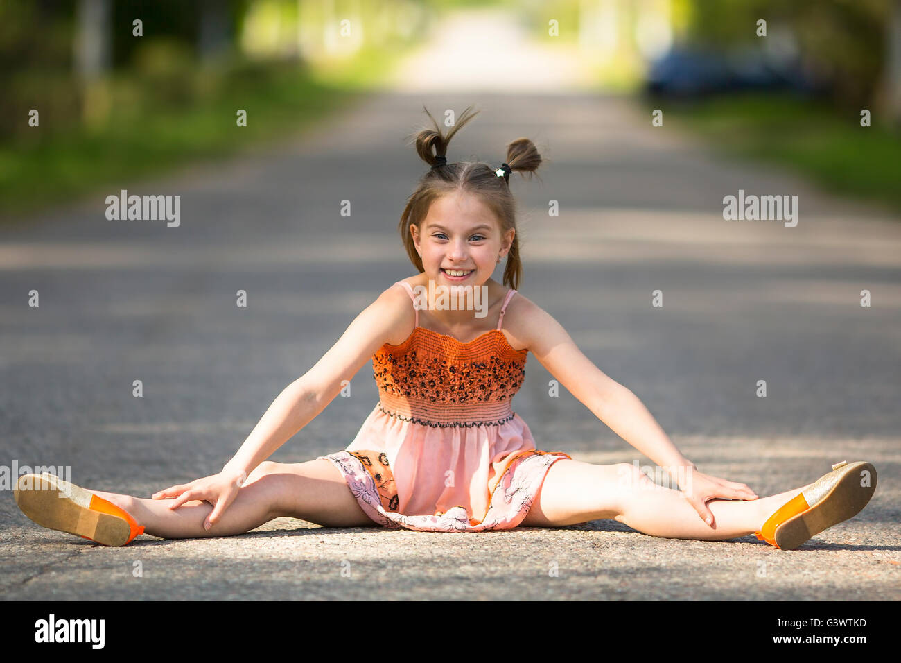 Joyeuse petite fille est assise sur la route. Banque D'Images