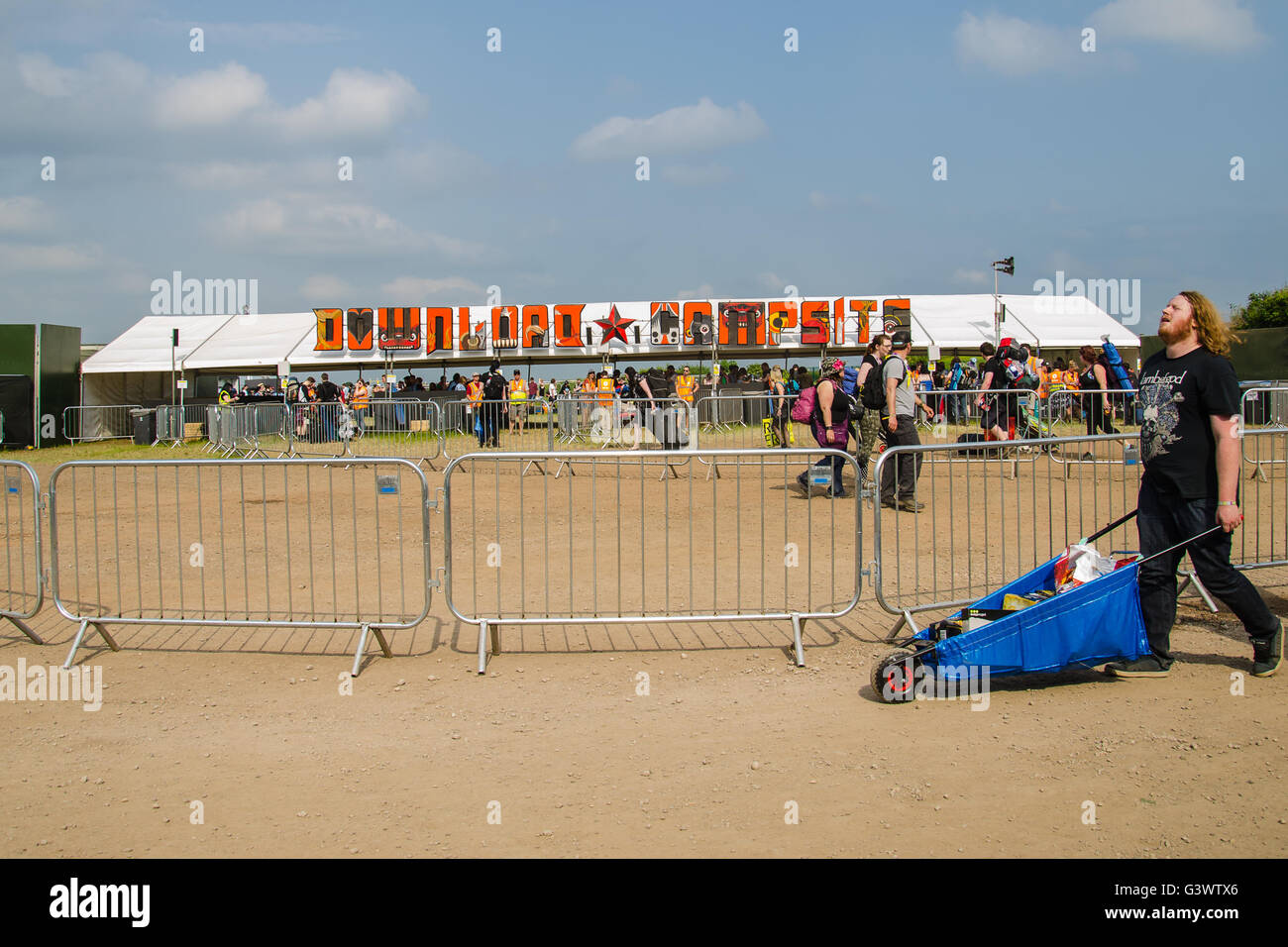 La chaleur du soleil et la poussière au Download festival camping, l'homme a l'air épuisé de voitures barrow après la longue promenade avec pignon camp Banque D'Images