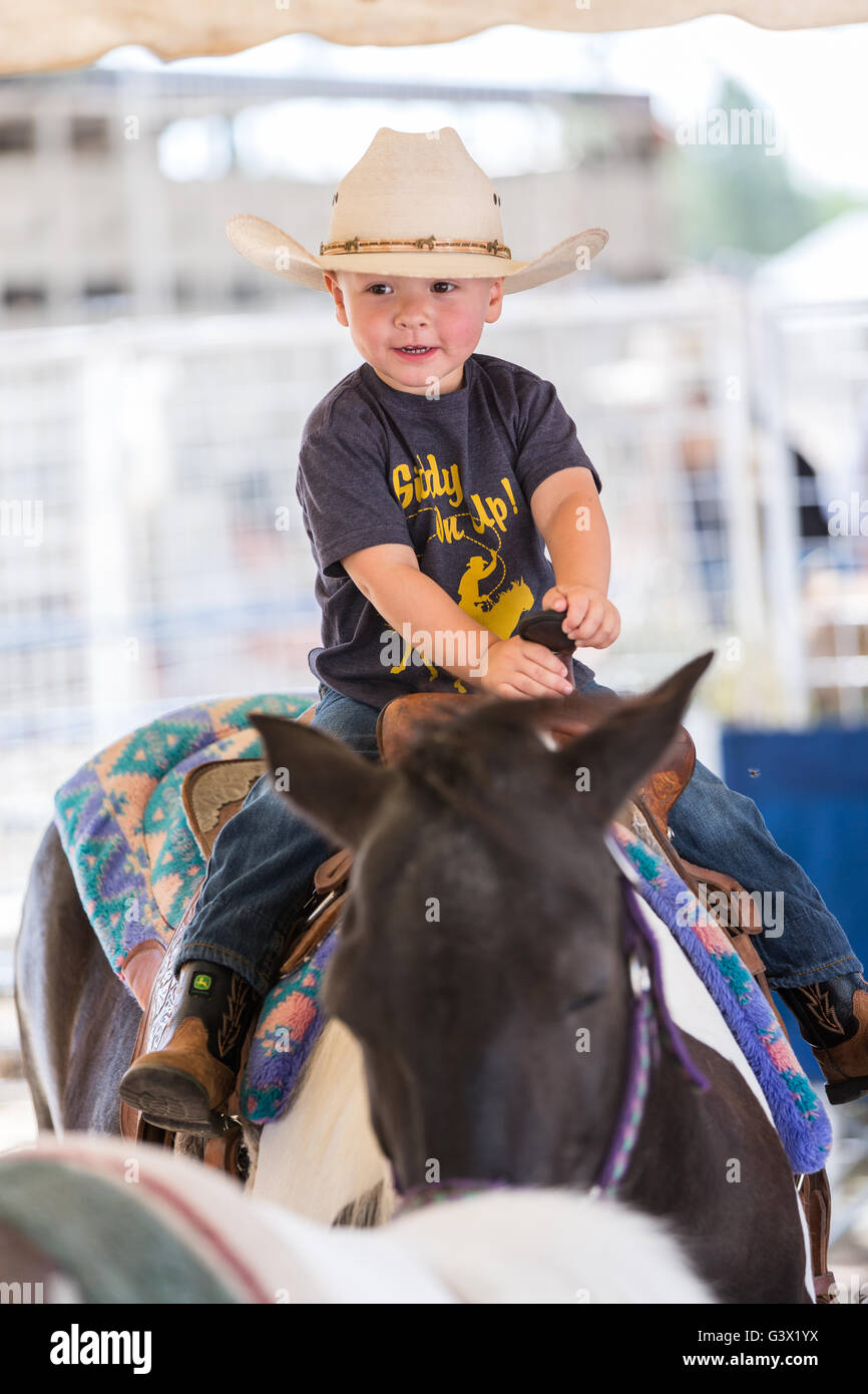 Un jeune garçon monte un poney sous l'œil attentif de son père au cours de Cheyenne Frontier Days le 25 juillet 2015 à Cheyenne, Wyoming. Frontier Days célèbre les traditions de l'ouest cowboy avec un rodéo, défilé et juste. Banque D'Images