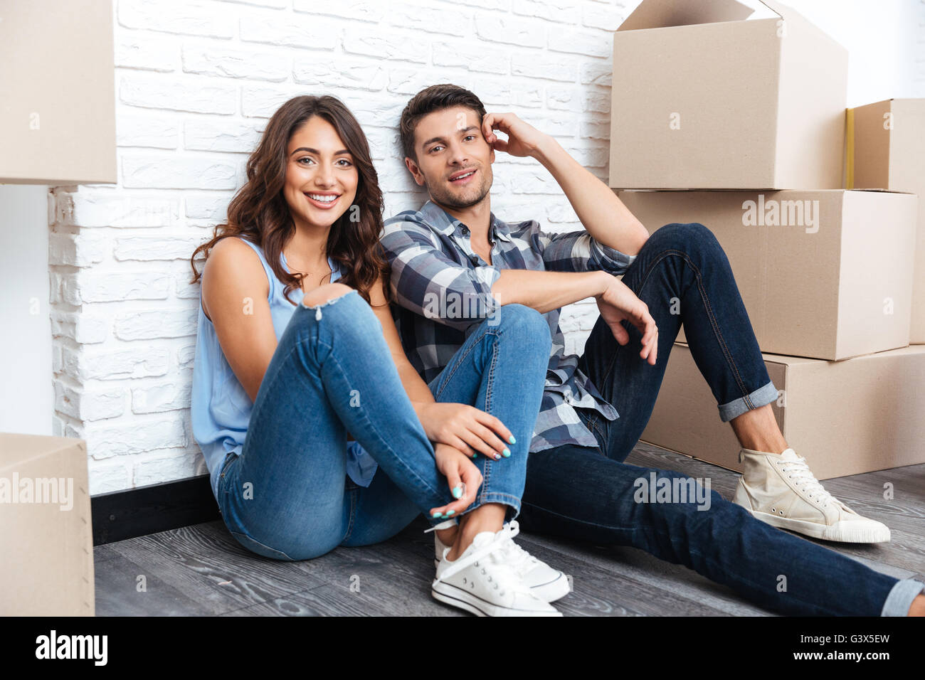 Happy young couple sitting on floor autour de cartons après l'achat de maison Banque D'Images